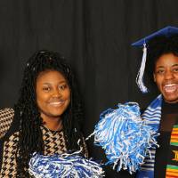 two students laughing with pom poms